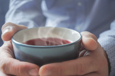 Mann hält dampfende Tasse Tee