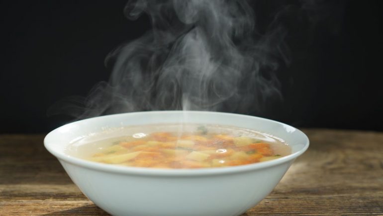 Suppemschüssel mit dampfender Hühnersuppe